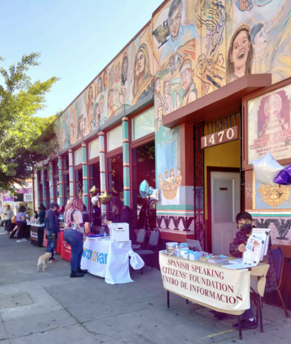 Outdoor community event at SSCF. Booths, resources, and a vibrant mural engage attendees.