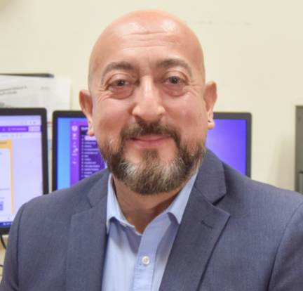 Headshot of Executive Director Christopher Nery Martinez in a blue suit, smiling.
